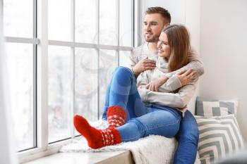 Happy couple resting near window at home�