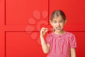 Cute little girl with toothbrush on color background�