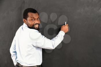 African-American teacher writing on blackboard in classroom�