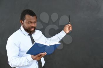 African-American teacher pointing at blackboard in classroom 