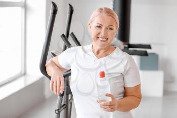 Sporty mature woman with bottle of water in gym�