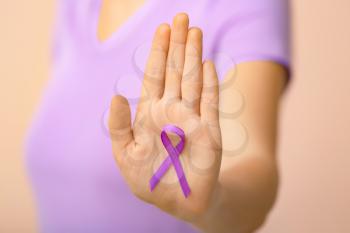 Woman with violet ribbon on color background, closeup. Domestic violence concept�