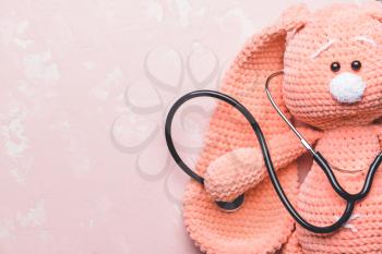 Stethoscope and baby toy on color background�