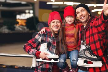 Happy family with ice skates near rink�