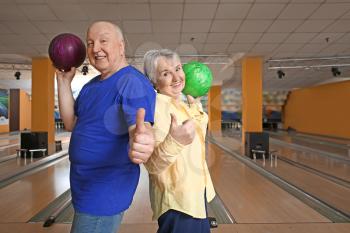 Senior couple showing thumb-up in bowling club�