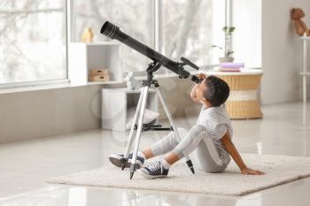 Little African-American boy with telescope at home�