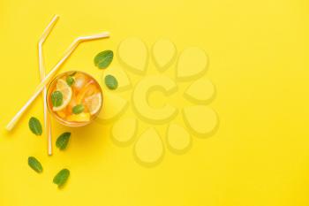 Glass of tasty cold ice tea on color background�