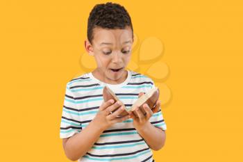 Cute African-American boy with sweet chocolate egg on color background�