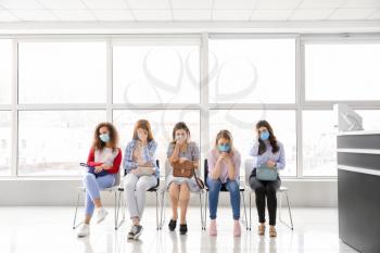 Patients with protective masks sitting in hall of clinic. Concept of epidemic�