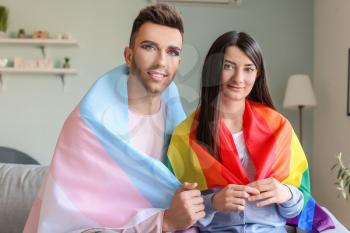 Portrait of young transgender couple with flags at home�