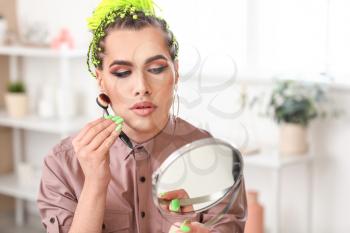 Transgender woman applying makeup at home�