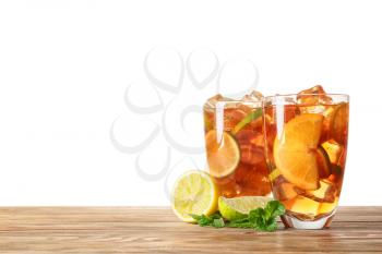 Glasses of tasty cold ice tea on table against white background�