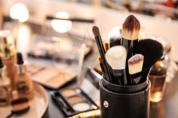 Brushes and different cosmetics on table of makeup artist�