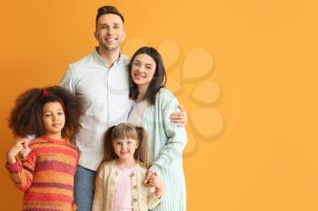 Happy couple with little adopted children on color background�