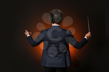 Senior male conductor on dark background�