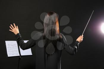 Young female conductor on dark background�
