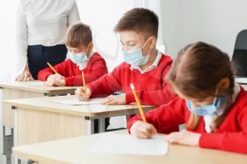 Pupils in medical masks passing exam at school. Concept of epidemic�