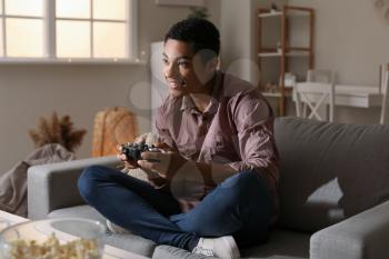 African-American teenage boy playing video game at home in evening�