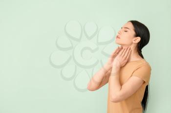 Young woman with thyroid gland problem on color background�
