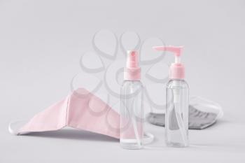 Bottles with disinfectant and protective masks on grey background�