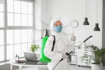 Worker in biohazard suit disinfecting office�