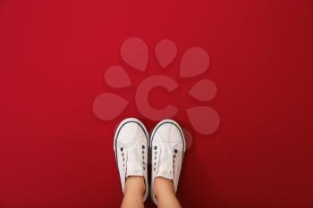 Legs of girl wearing shoes on color background�