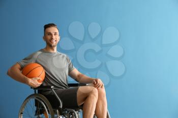 Young basketball player sitting in wheelchair against color background�