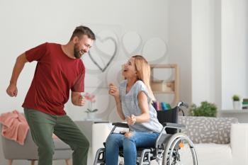 Beautiful woman in wheelchair with man dancing at home�