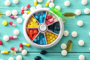 Plastic container with pills on color wooden background�