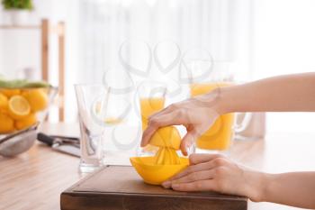 Woman squeezing fresh lemon juice in kitchen�