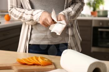 Woman wiping knife with paper towel in kitchen�
