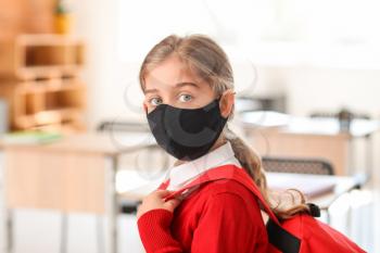 Little girl wearing medical mask at school�