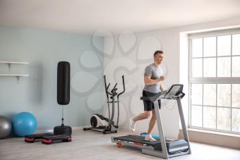 Young man training on treadmill in gym�