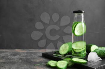 Bottle of infused cucumber water on dark background 