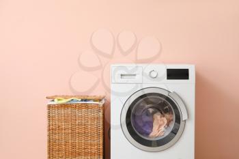 Washing machine and basket with laundry near color wall�