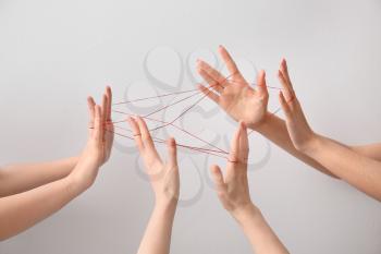 Hands tied with red thread on light background. Unity concept�