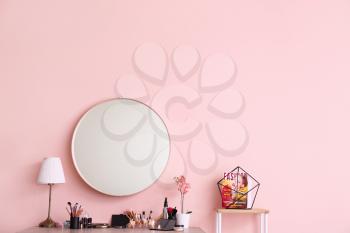 Table with decorative cosmetics and mirror in modern makeup room�