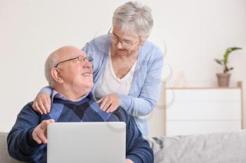 Senior couple with laptop at home�