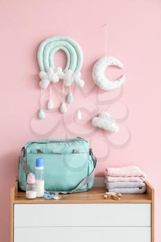 Bottles of milk for baby with pacifiers and clothes on chest of drawers�