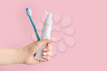 Hand with tooth brush and paste on color background�