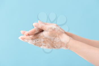 Woman washing hands with soap on color background�