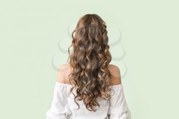 Beautiful young woman with stylish hairdo on color background, back view�