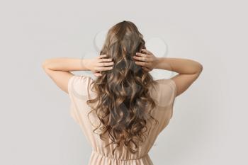 Beautiful young woman with stylish hairdo on grey background, back view�