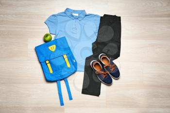 Stylish school uniform with backpack on wooden background�