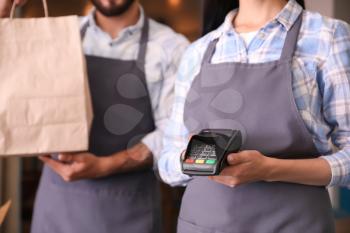 Young waiters with food for delivery and payment terminal in restaurant 