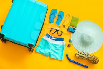 Set of beach accessories with suitcase on color background. Concept of rest abroad�