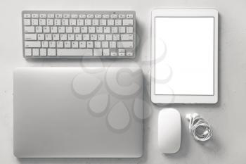 Modern laptop, keyboard, tablet computer, PC mouse and earphones on light background�