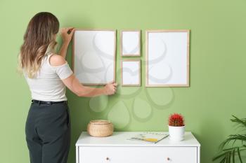 Woman hanging blank photo frames on wall�