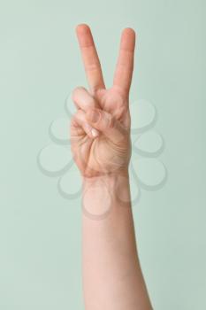 Hand showing letter V on color background. Sign language alphabet�