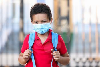 Little African-American boy in medical mask near school. Coronavirus epidemic�